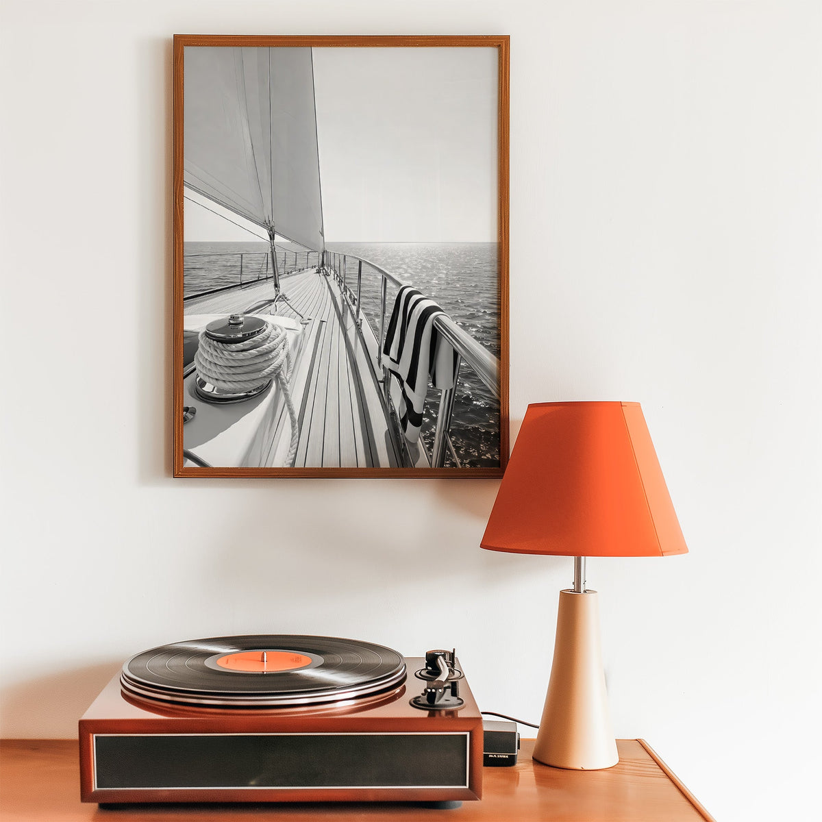 Sailboat deck with rope coil and striped towel print in a walnut frame above a record player and orange lamp
