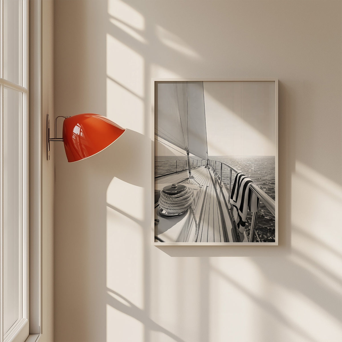Sailboat deck with rope coil and striped towel print in a white frame on a sunlit wall beside a red sconce