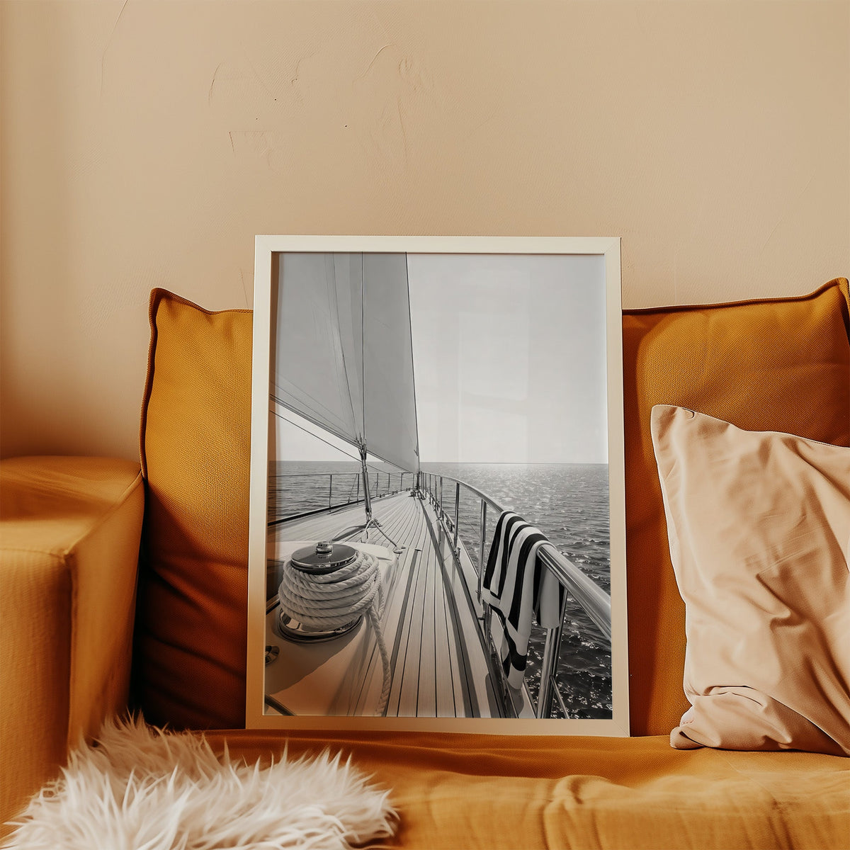 Sailboat deck with rope coil and striped towel print in a white frame leaning on a mustard velvet sofa