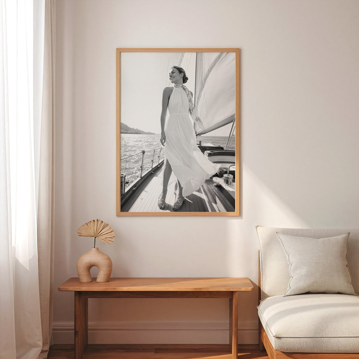 Black and white woman in white dress on sailboat print in an oak frame above a narrow console with an arched vase