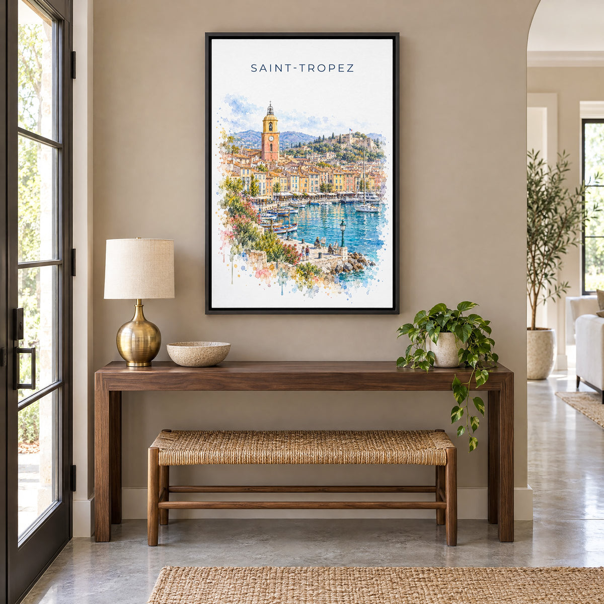 Saint-Tropez watercolor print as a black floater canvas above a walnut console and woven bench in an entryway