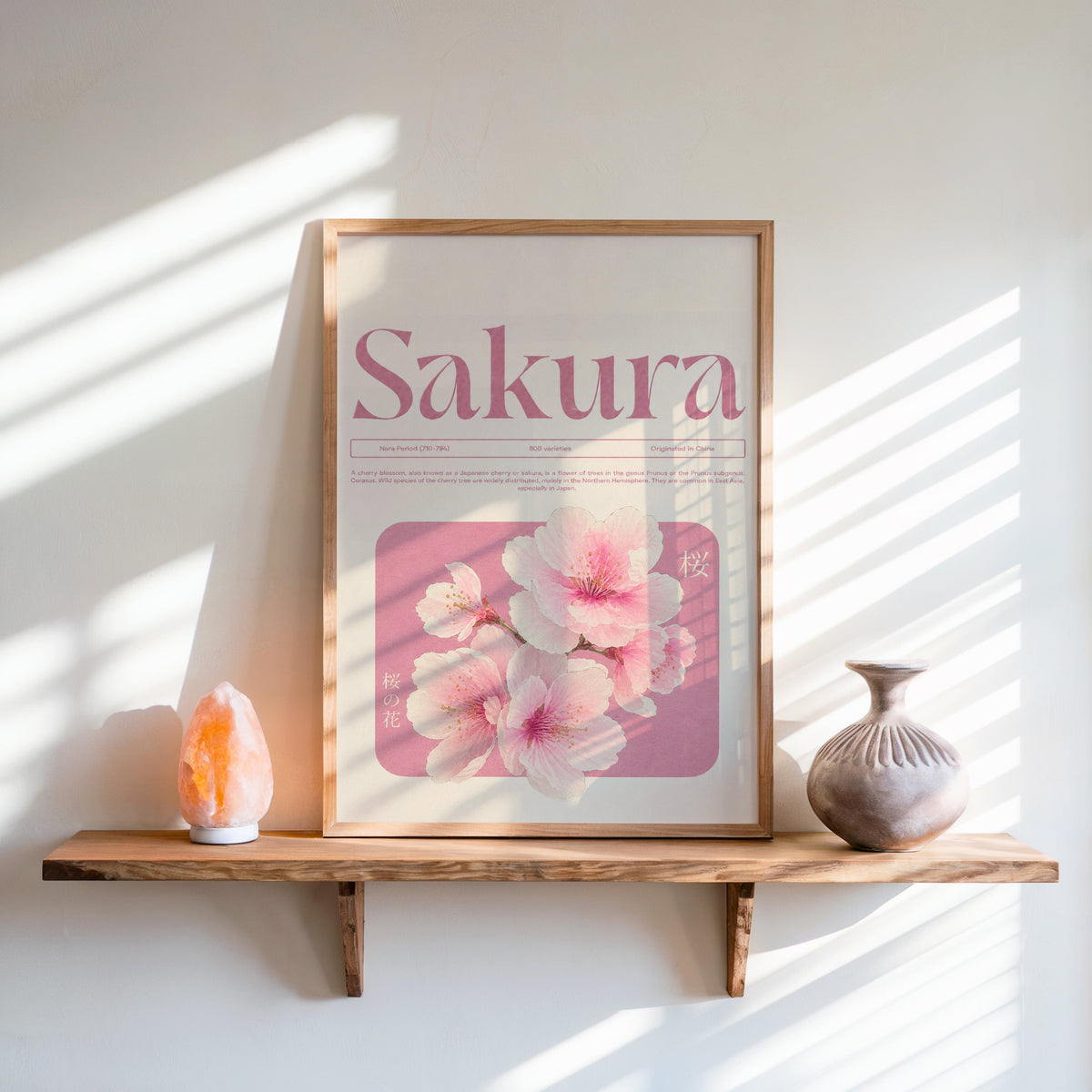 pink sakura blossom typography print in an oak frame on a live-edge wall shelf with a salt lamp and clay vase
