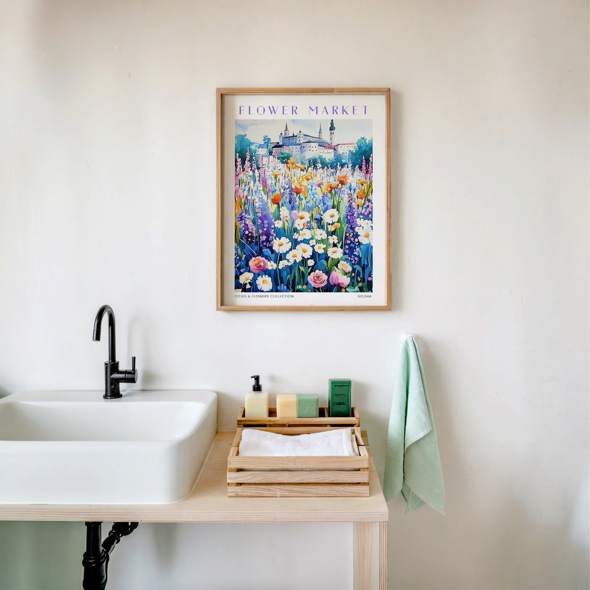 Salzburg flower market print in an oak frame above a white bathroom sink with folded towels