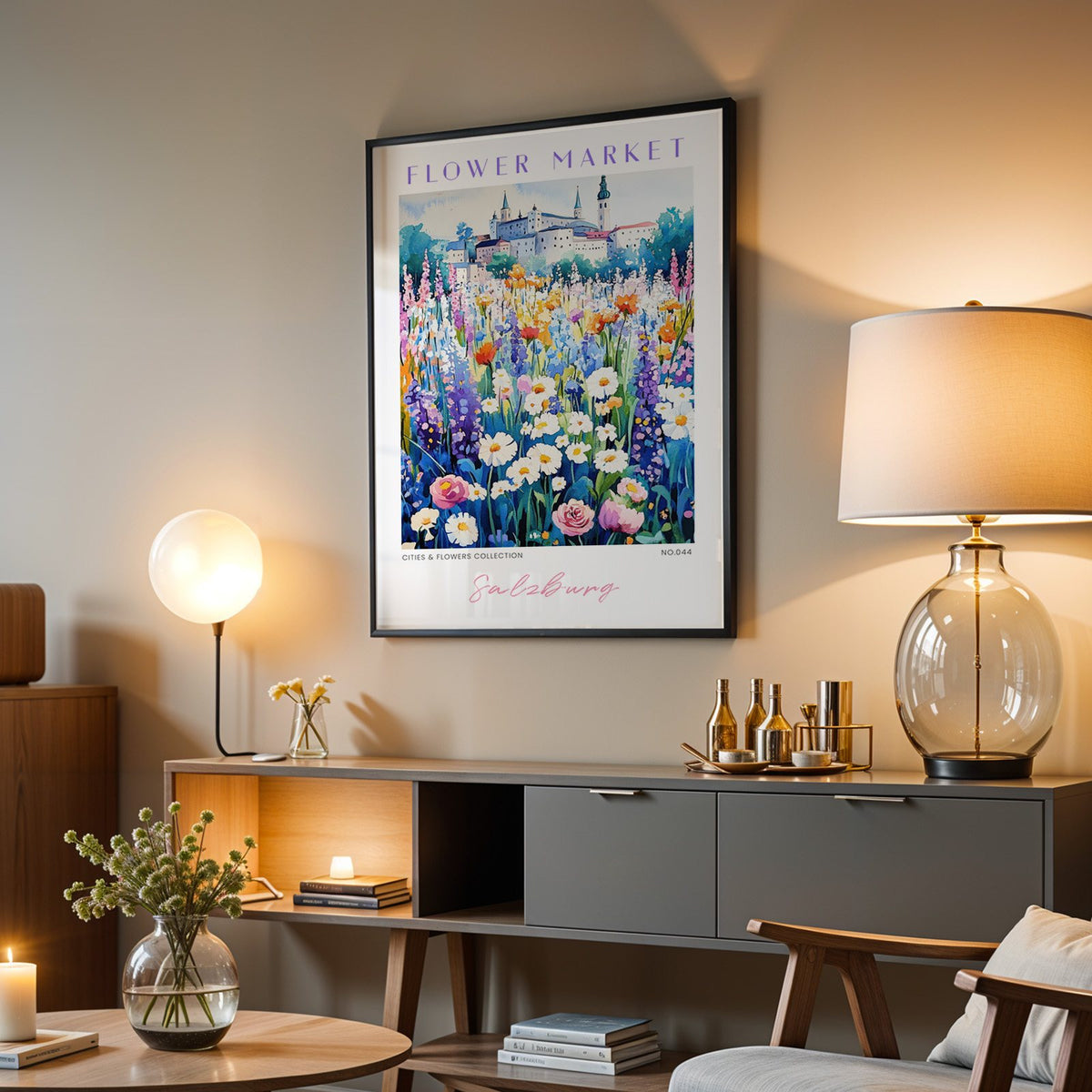 Salzburg flower market print in a black frame above a grey media console with a glass table lamp