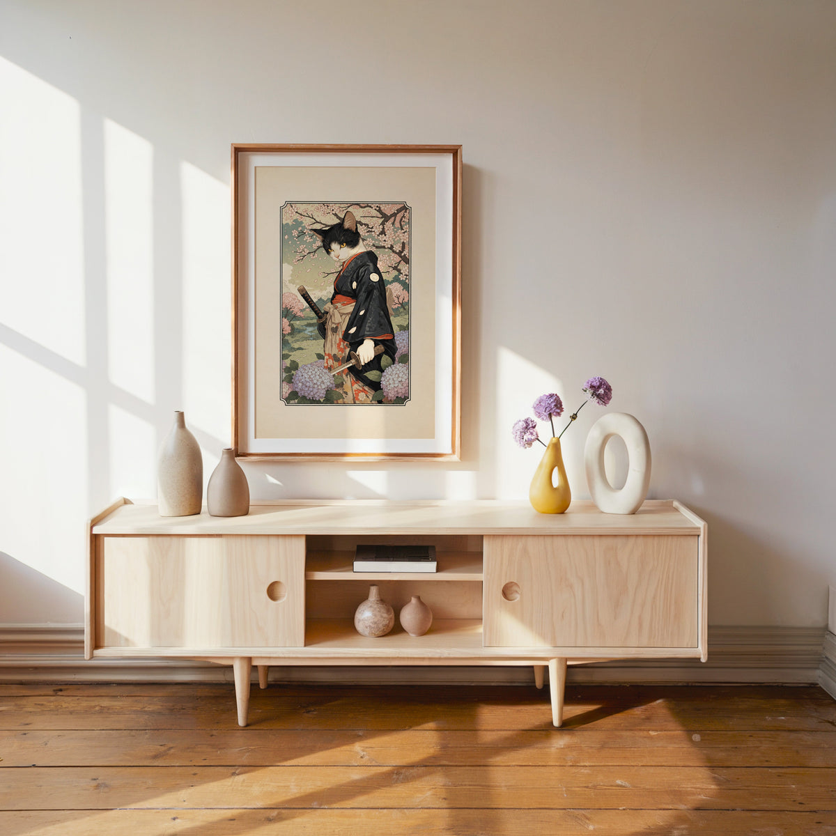 samurai cat with katana print shown in a wood frame with a white mat above a pale wood media console