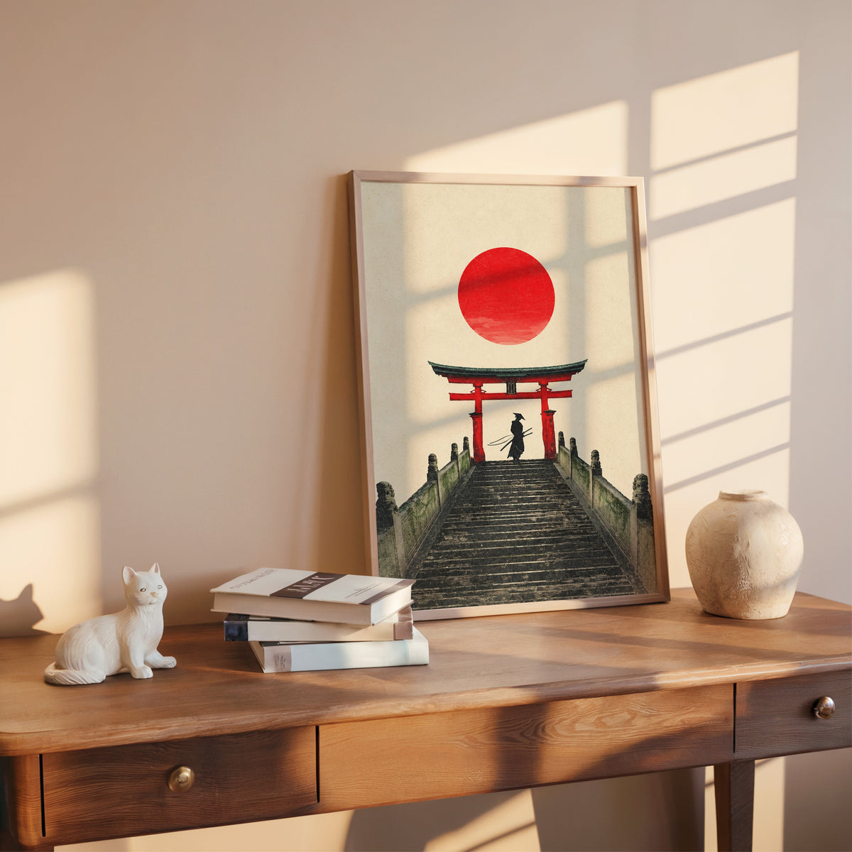 samurai under red torii gate print shown in a rose gold frame leaning on a wooden writing desk with books