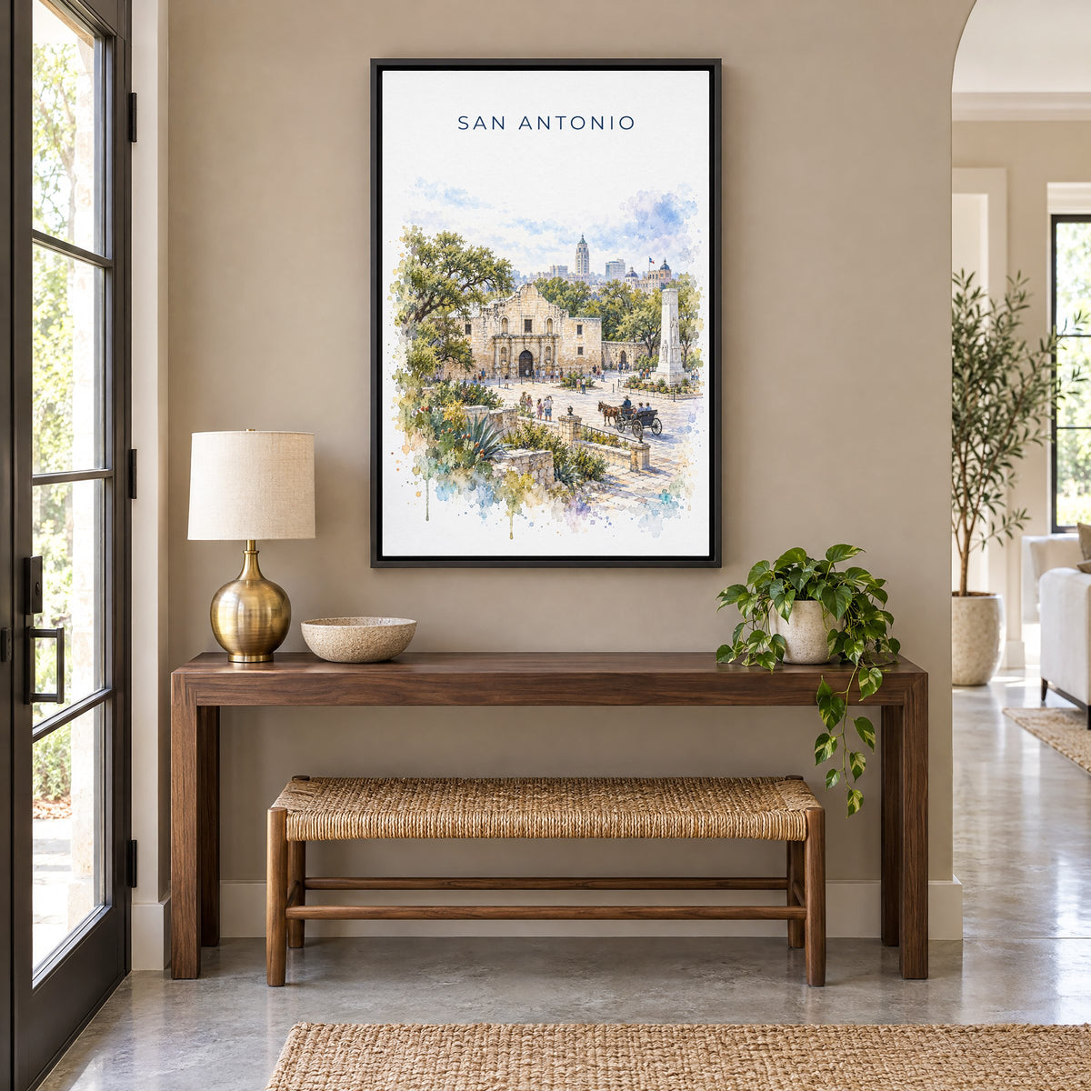San Antonio watercolor print as a black floater canvas above a walnut console and woven bench in an entryway