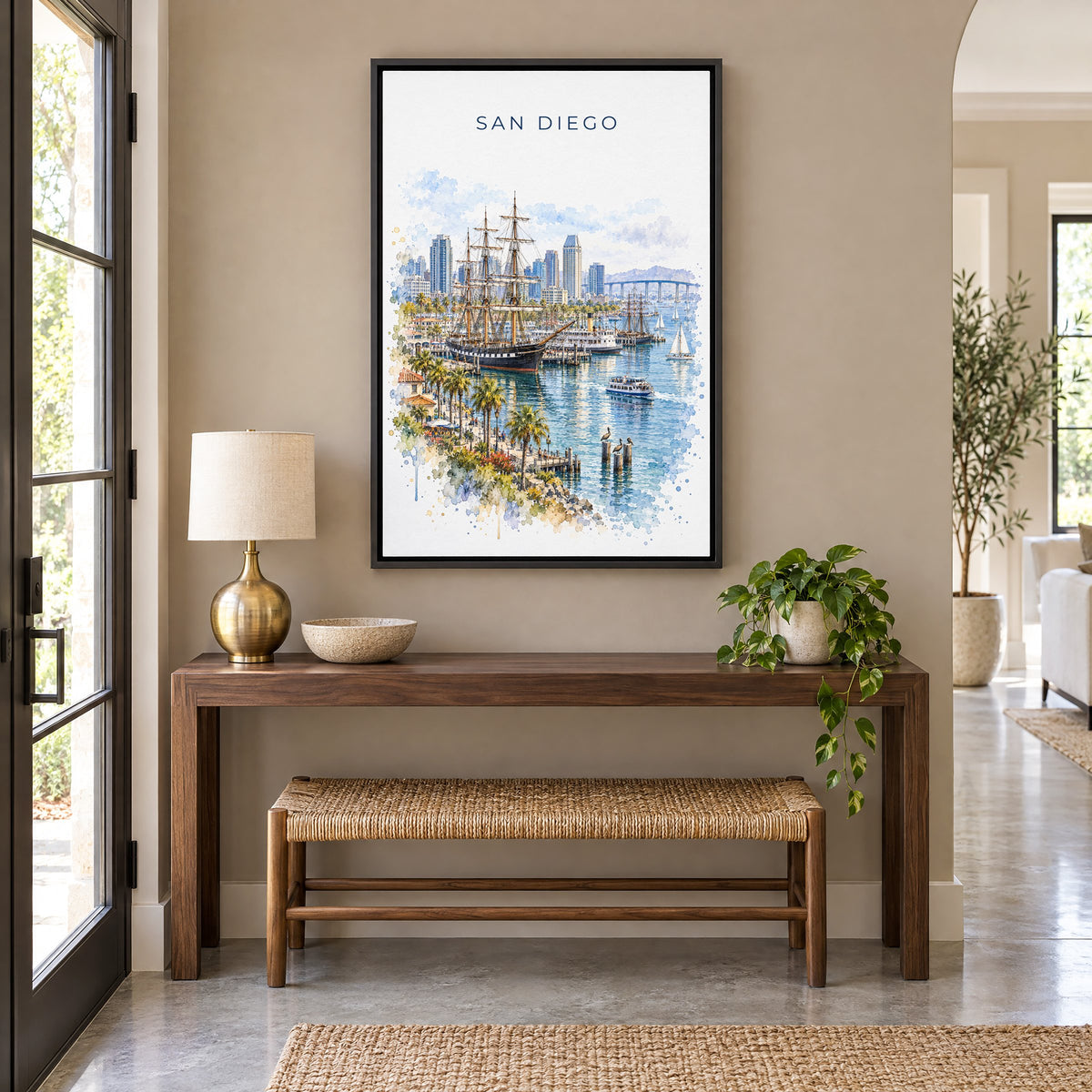 San Diego Bay watercolor print as a black floater canvas above a walnut console and woven bench in an entryway