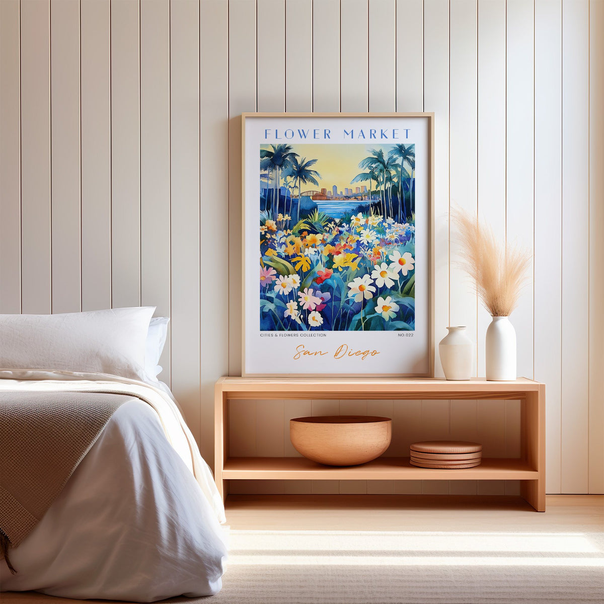 San Diego flower market print in an oak frame on a wood bench against a white shiplap bedroom wall with pampas grass