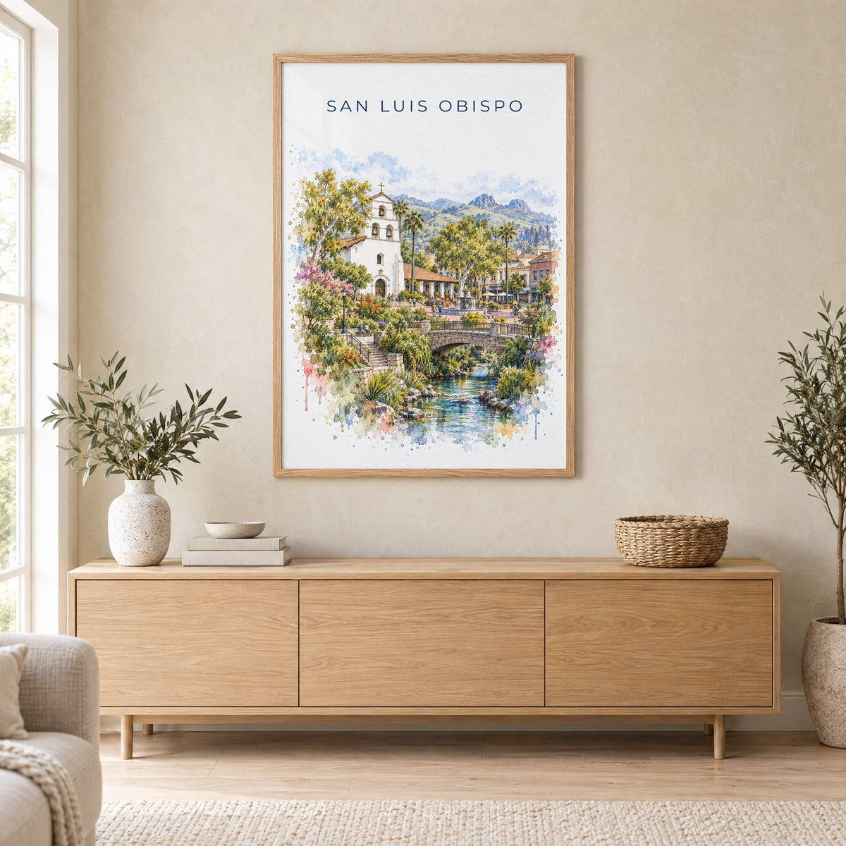 San Luis Obispo watercolor print in an oak frame above a light wood sideboard in a Scandinavian living room