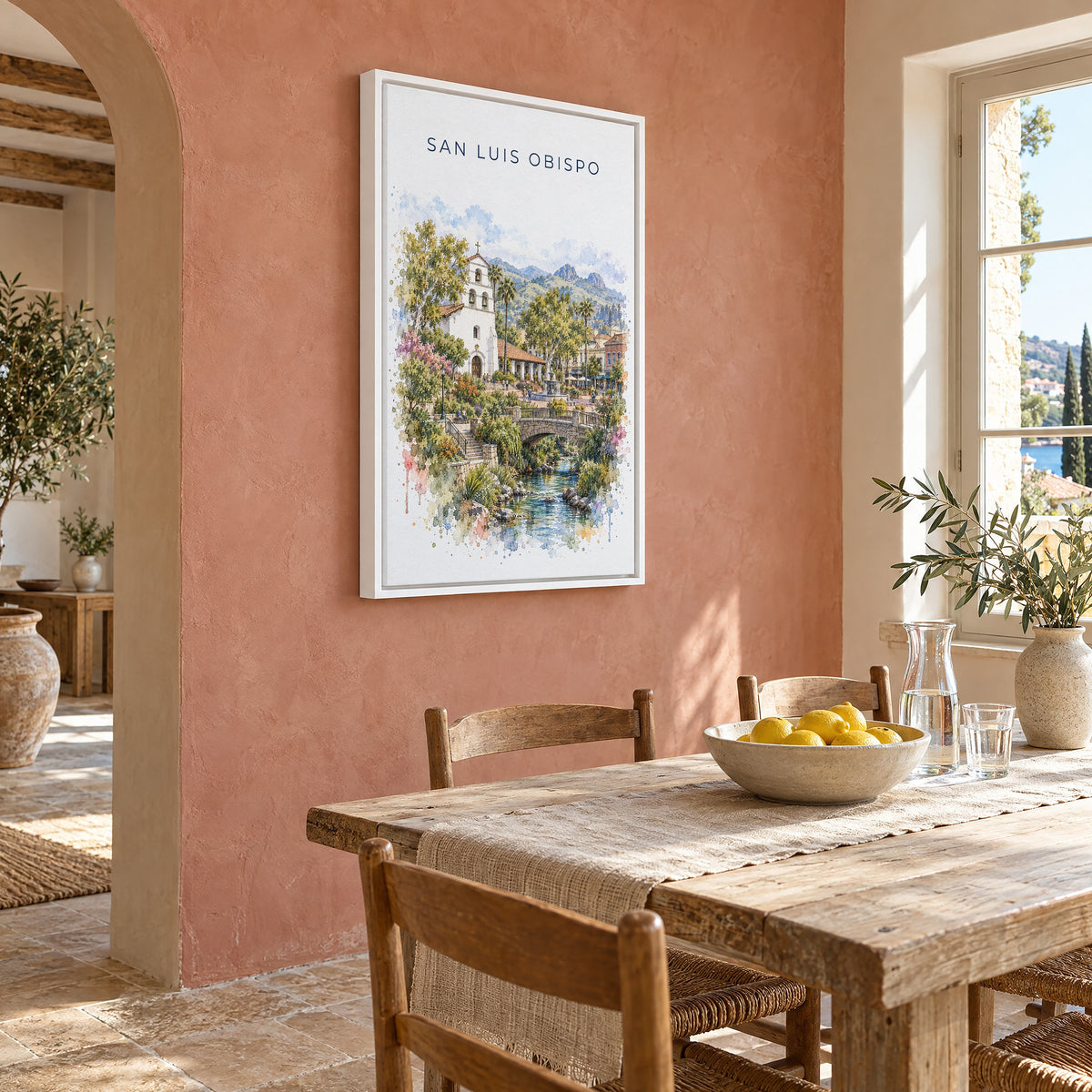San Luis Obispo watercolor print as a white floater canvas on a terracotta wall above a rustic dining table
