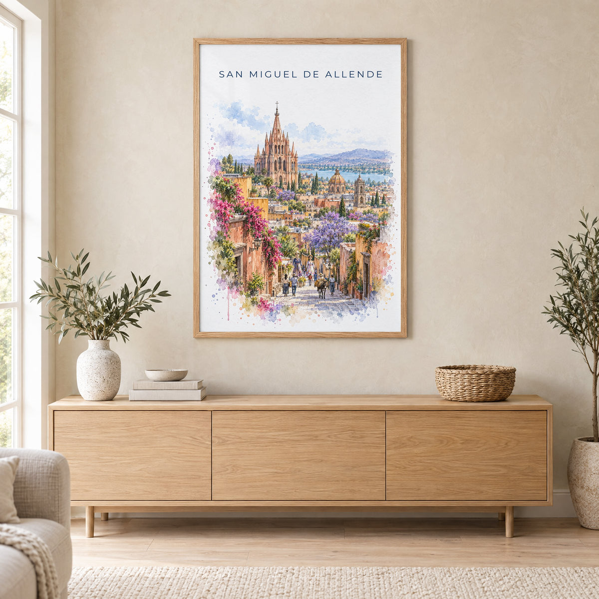 San Miguel de Allende watercolor print in an oak frame above a light wood sideboard in a Scandinavian living room