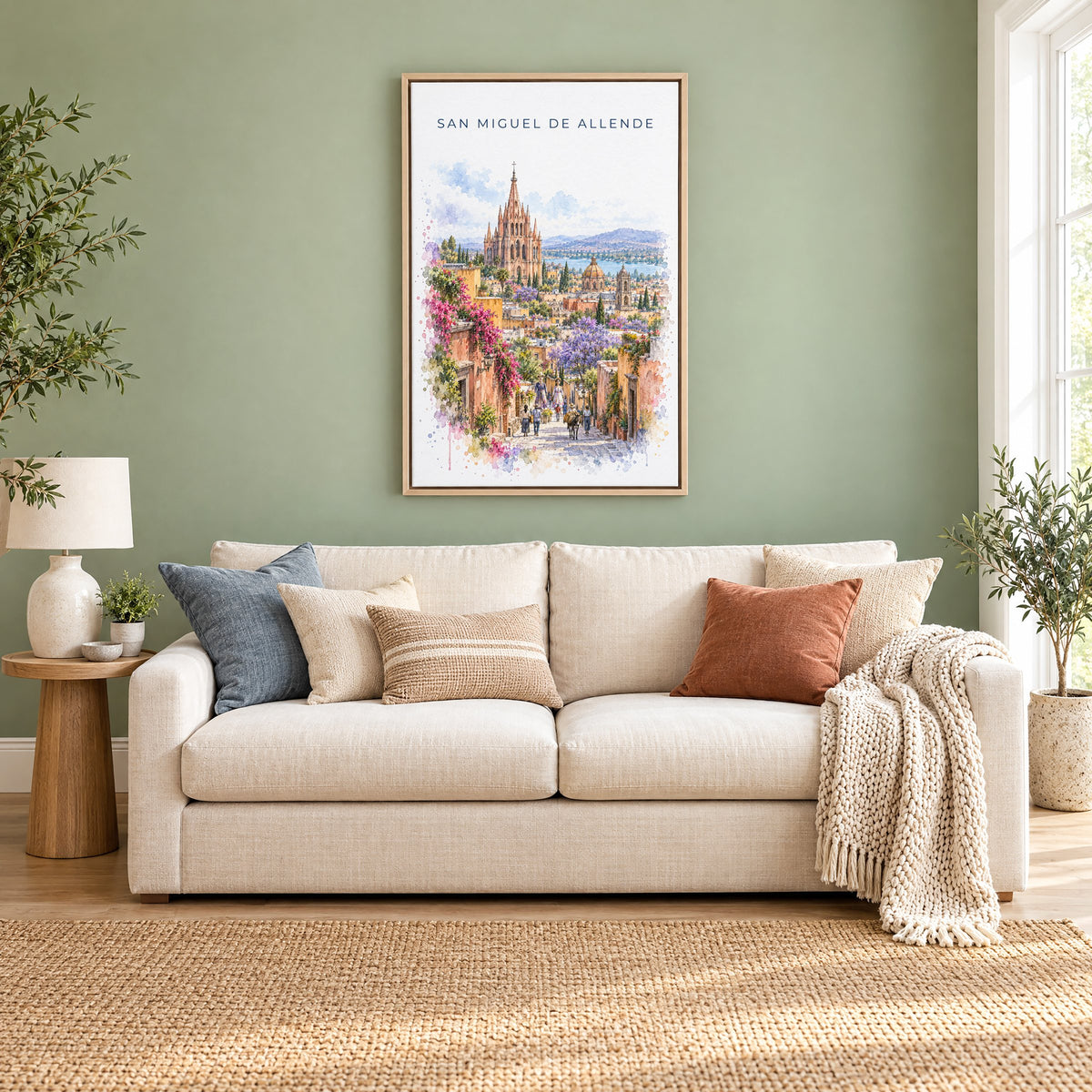 San Miguel de Allende watercolor print as a natural floater canvas above a cream linen sofa on a sage green wall