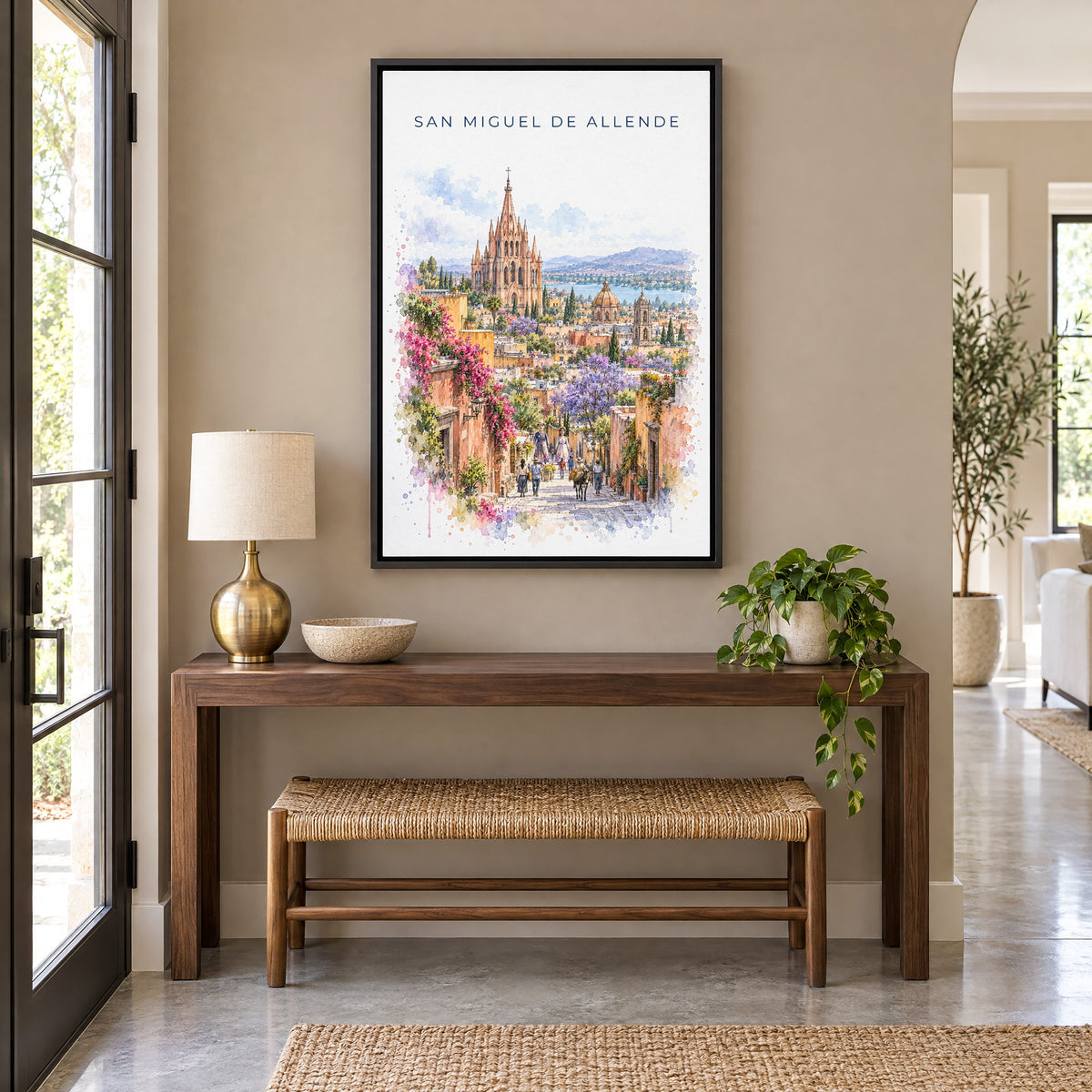 San Miguel de Allende watercolor print as a black floater canvas above a walnut console and woven bench in an entryway