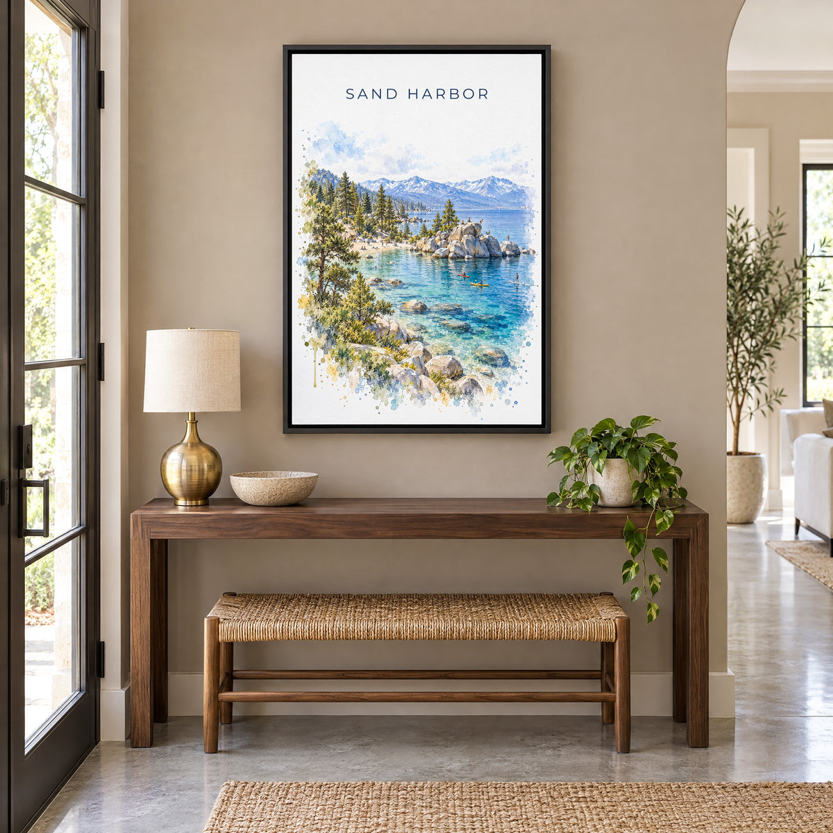 Sand Harbor watercolor print as a black floater canvas above a walnut console and woven bench in an entryway