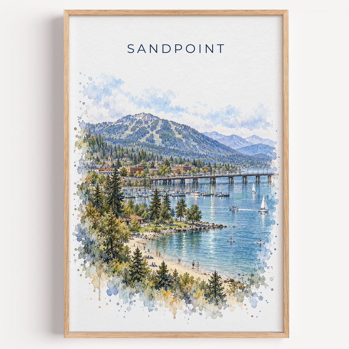 Sandpoint watercolor print in a light oak frame on a plain white wall
