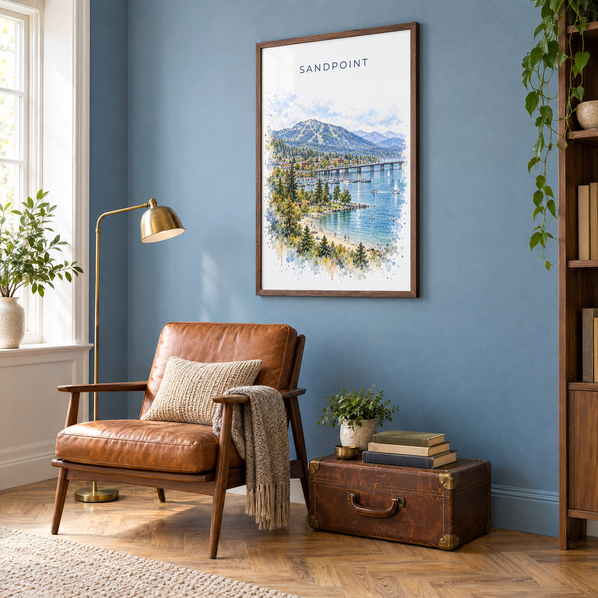 Sandpoint watercolor print in a walnut frame on a blue wall above a leather armchair in a reading nook