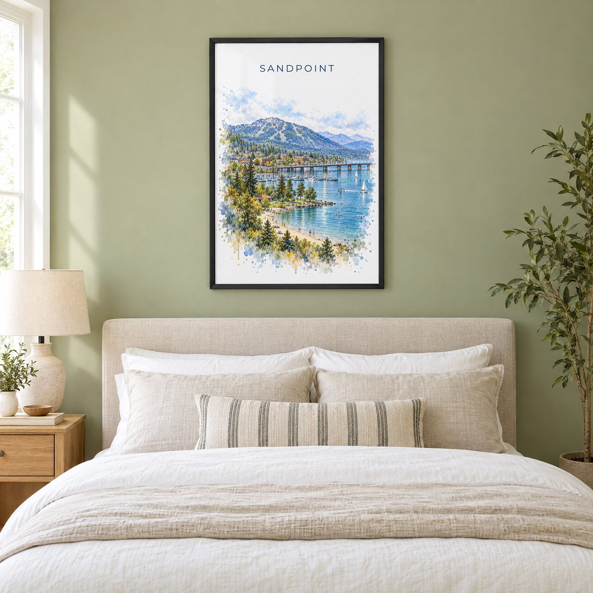 Sandpoint watercolor print in a black frame above an upholstered headboard in a sage green bedroom