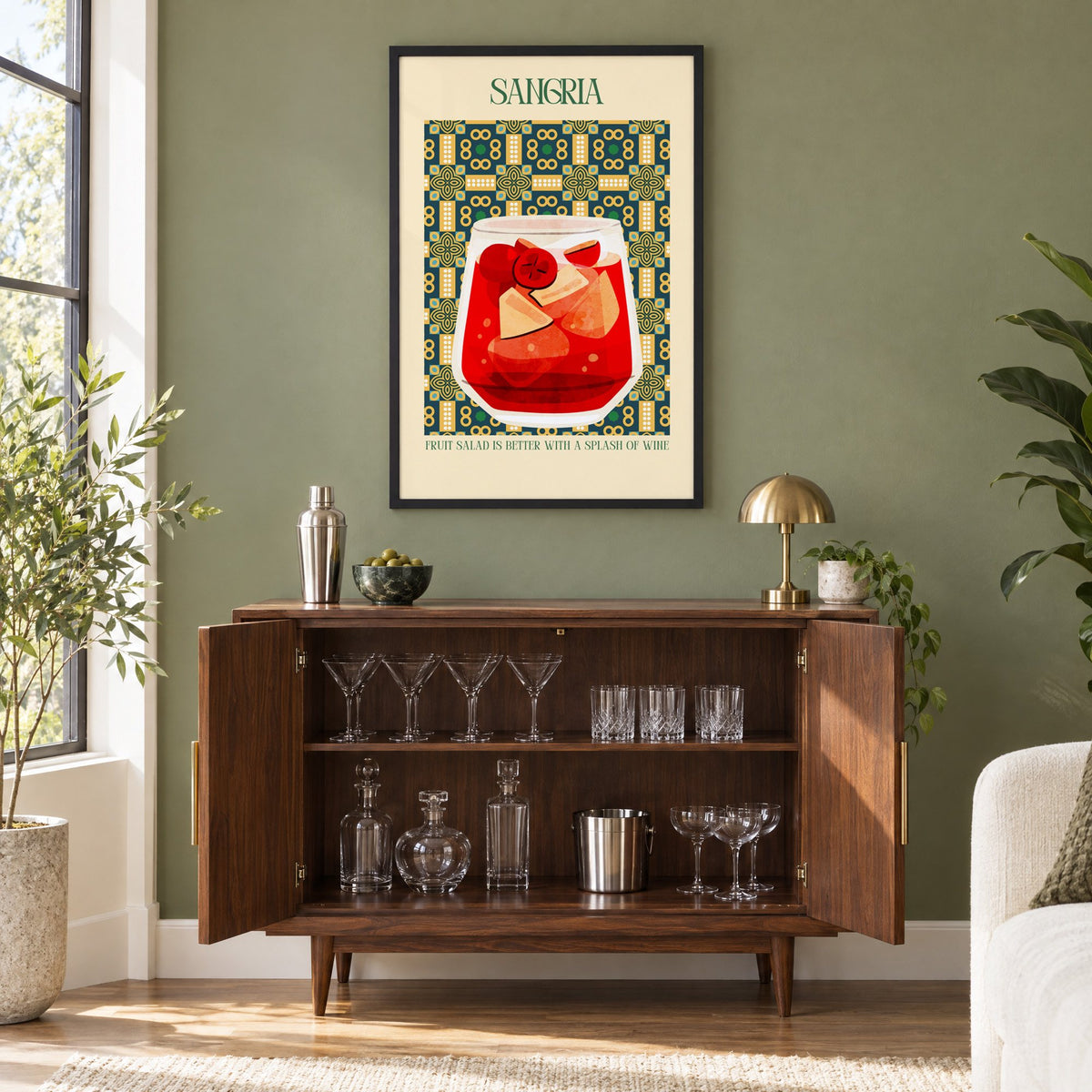 SANGRIA red glass patterned tile print in a black frame on an olive green wall above a walnut bar cabinet with glassware