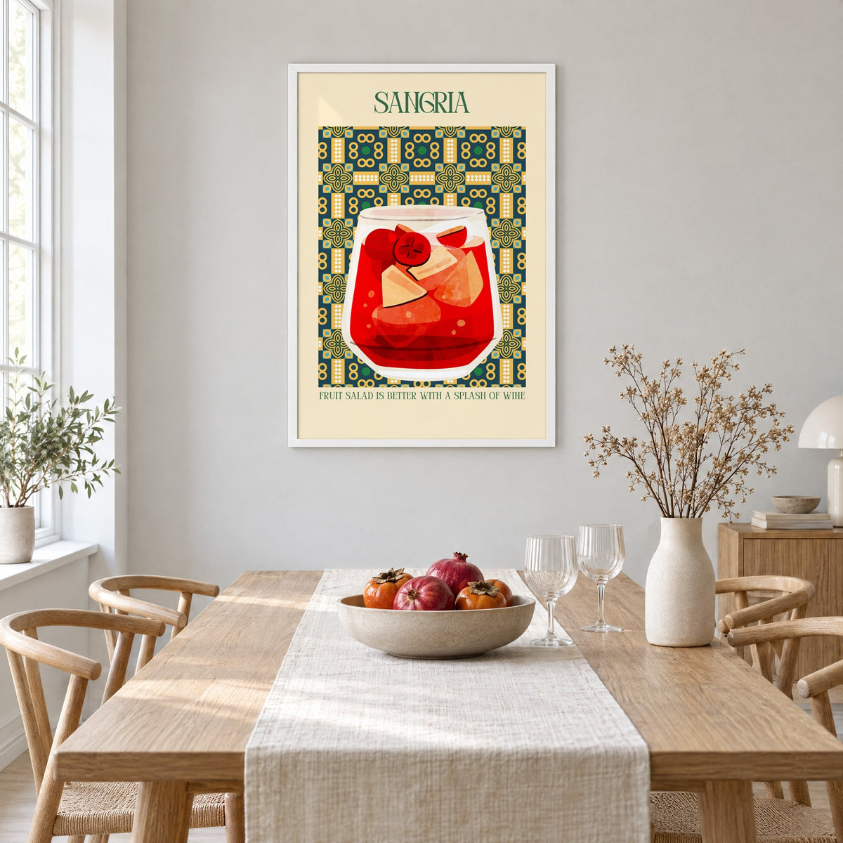 SANGRIA red glass patterned tile print in a white frame above a light oak dining table with a linen runner and fruit bowl
