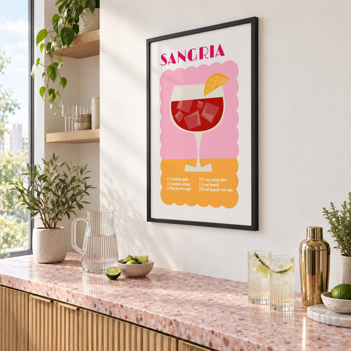 SANGRIA recipe pink and orange print in a black frame above a pink terrazzo cocktail counter with limes, seen at an angle