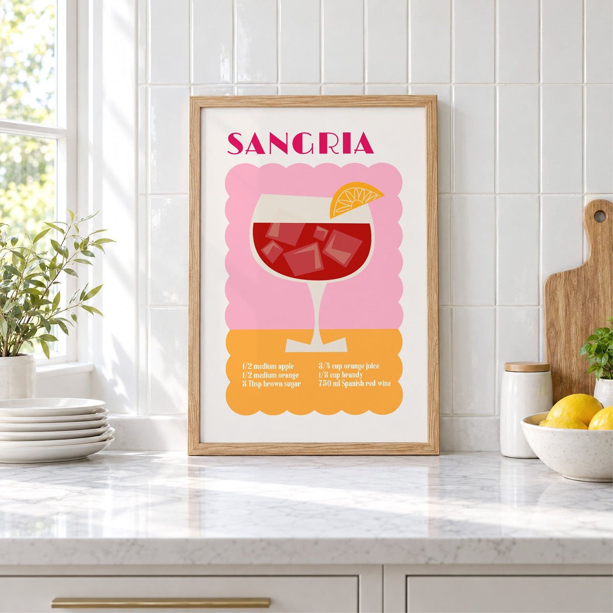SANGRIA recipe pink and orange print in an oak frame leaning on a marble counter by white tiles and lemons