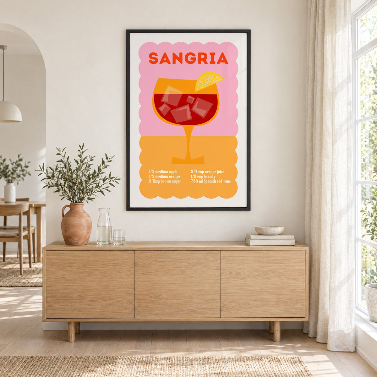 Sangria recipe pink and orange print in a black frame above an oak sideboard with a terracotta vase of olive branches