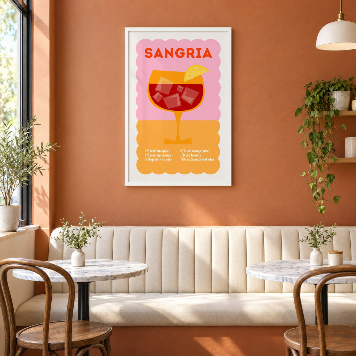 Sangria recipe pink and orange print in a white frame above a cream banquette on a terracotta cafe wall