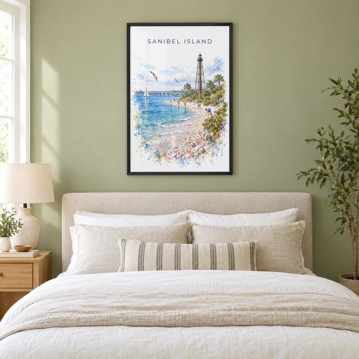 Sanibel Island watercolor print in a black frame above an upholstered headboard in a sage green bedroom