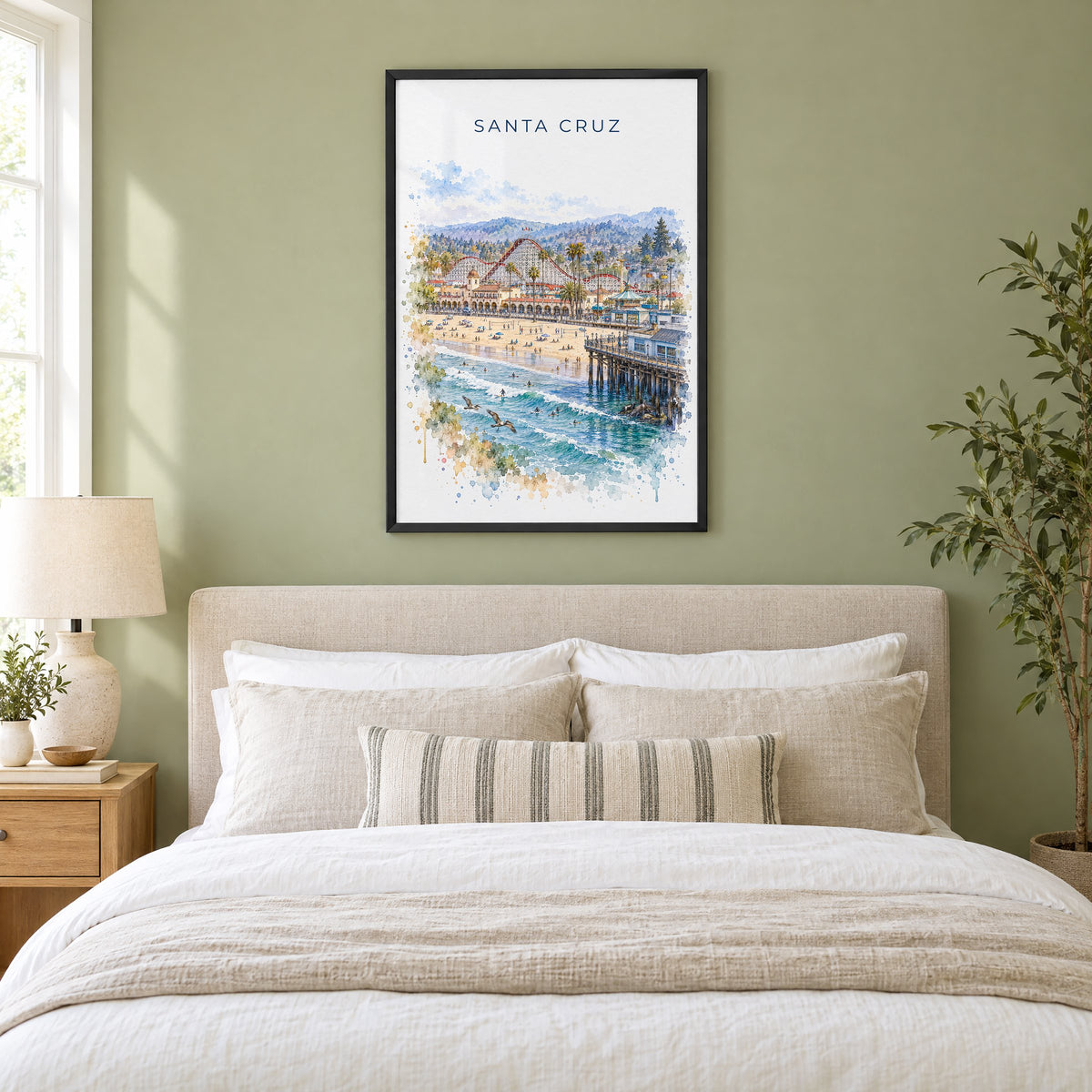 Santa Cruz, California watercolor print in a black frame above an upholstered headboard in a sage green bedroom