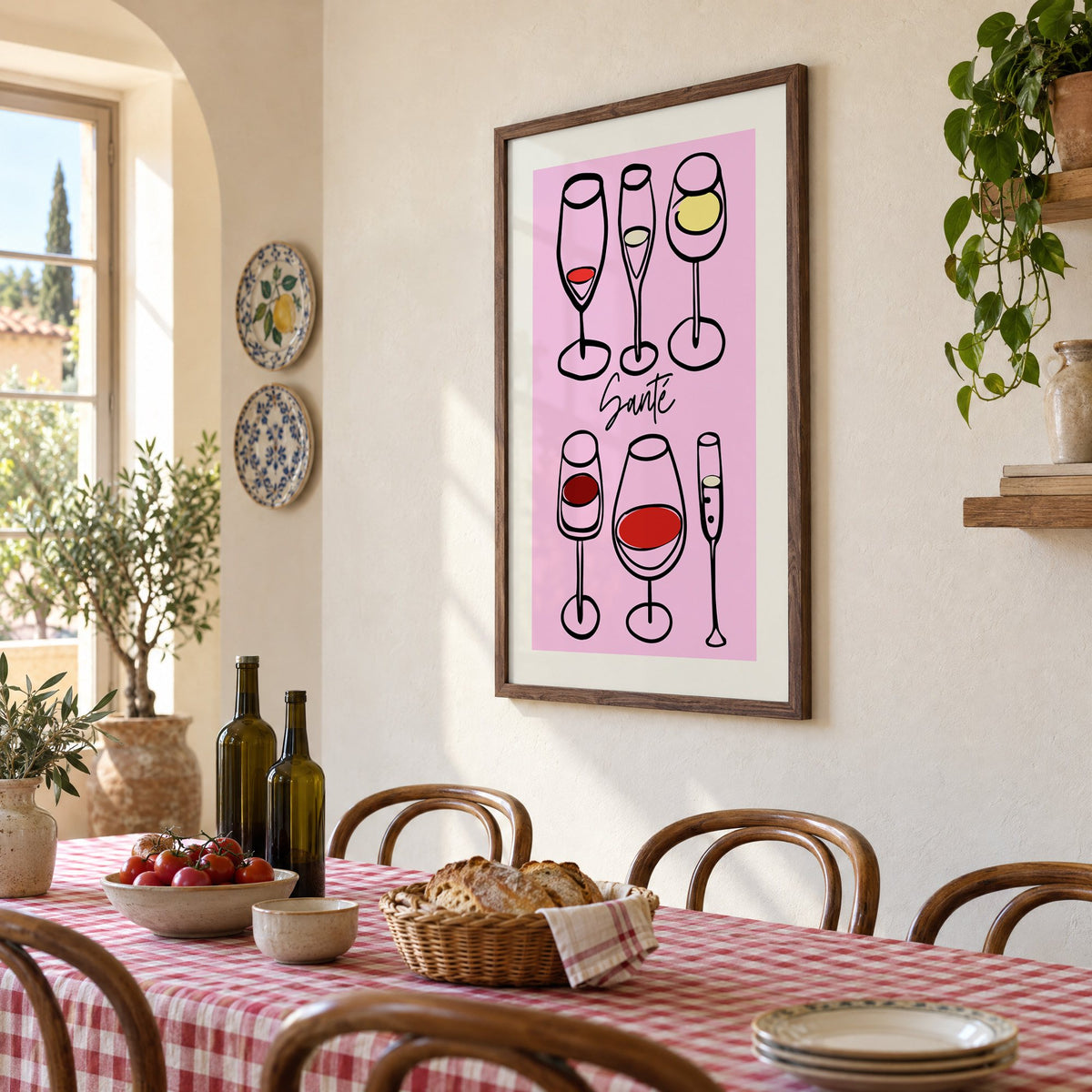 Santé wine glasses line art print in a walnut frame above a gingham-covered trattoria table, seen at an angle