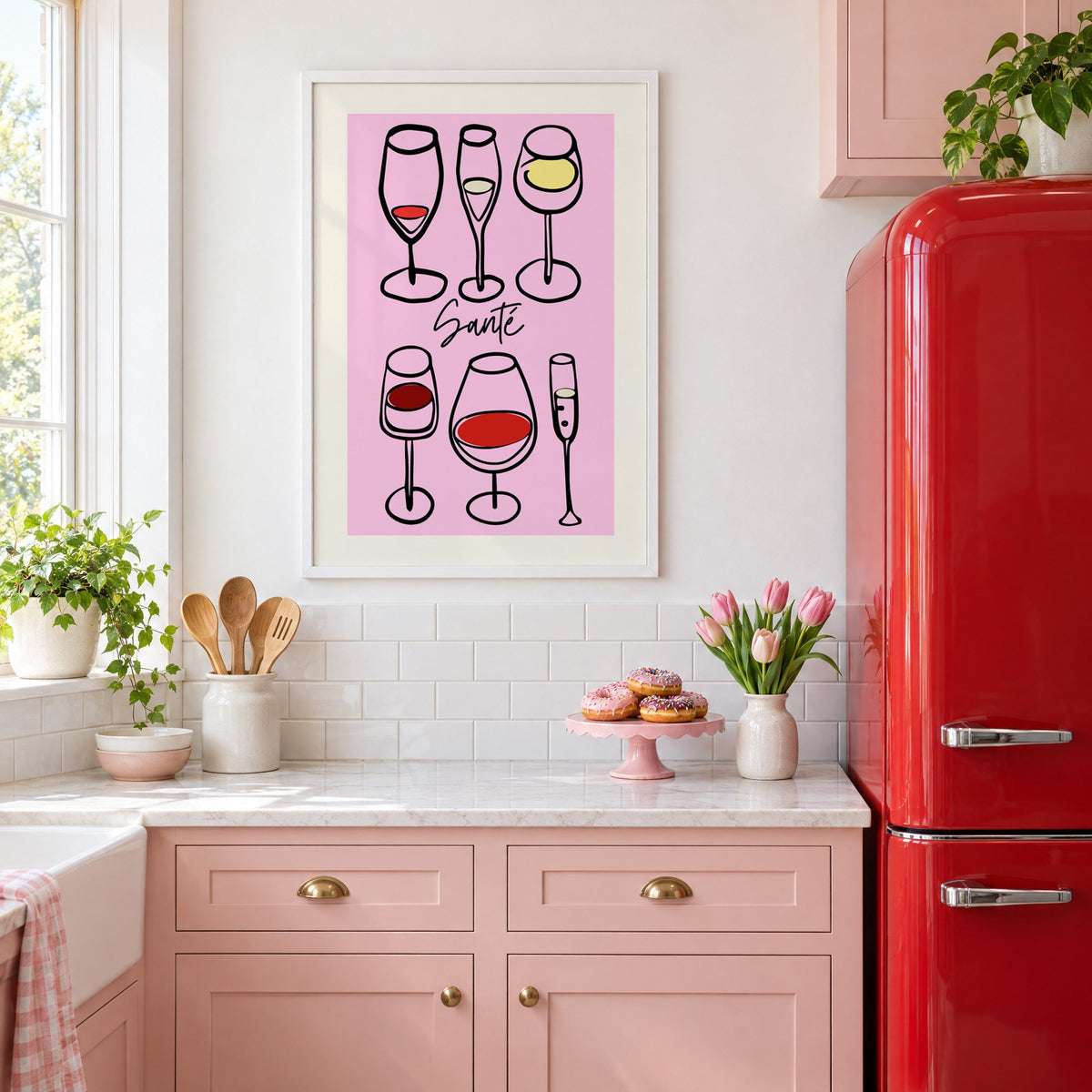 Santé wine glasses line art print in a white frame in a pink kitchen beside a red retro fridge