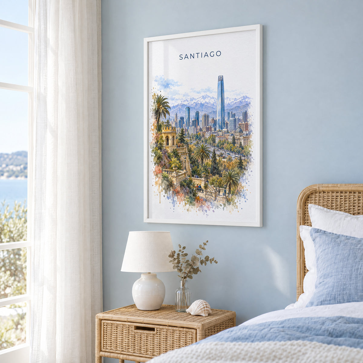 Santiago, Chile watercolor print in a white frame on a pale blue wall beside a rattan bed in a coastal bedroom
