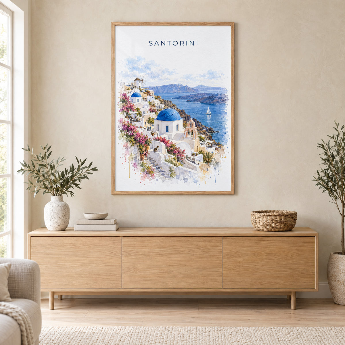 Santorini watercolor print in an oak frame above a light wood sideboard in a Scandinavian living room
