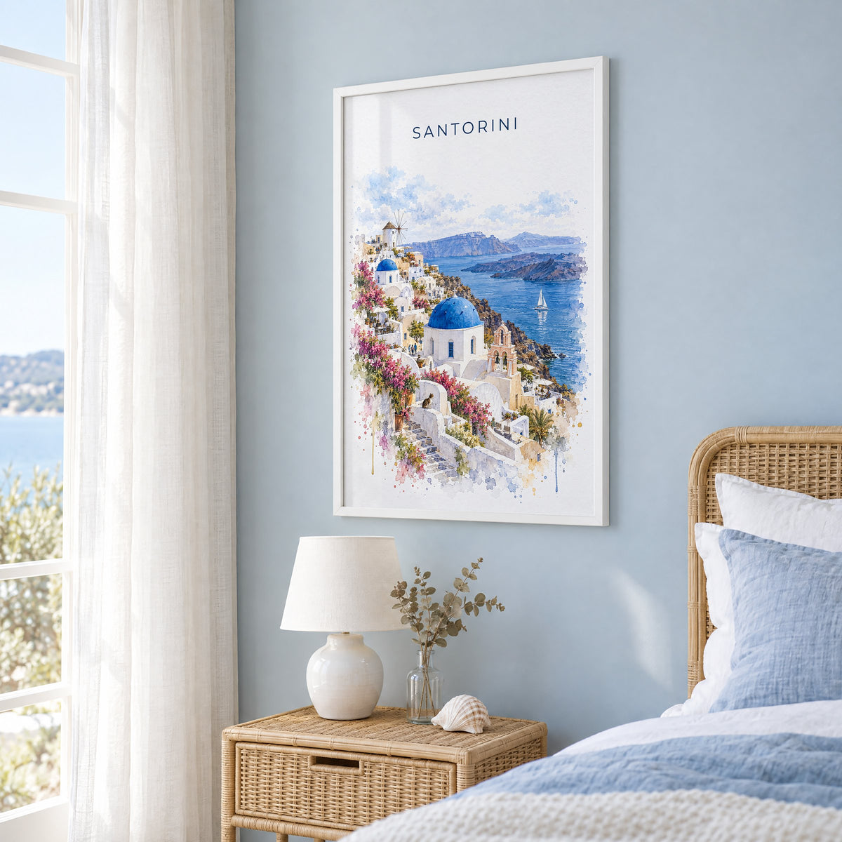 Santorini watercolor print in a white frame on a pale blue wall beside a rattan bed in a coastal bedroom
