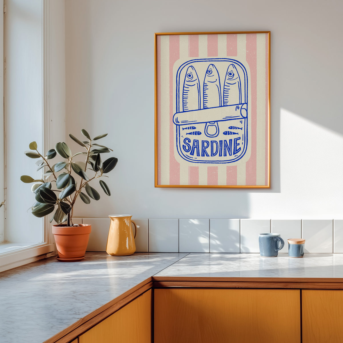 Sardine tin print in a gold frame above a marble counter with a yellow ceramic jug