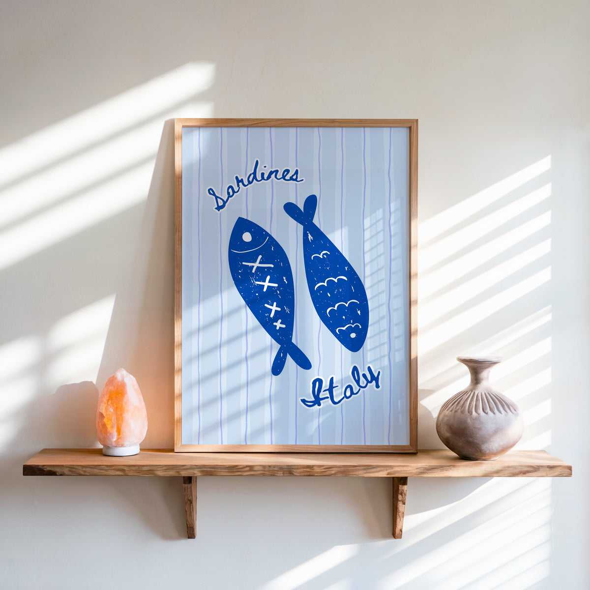 Sardines Italy print in an oak frame on a live-edge shelf beside a salt lamp