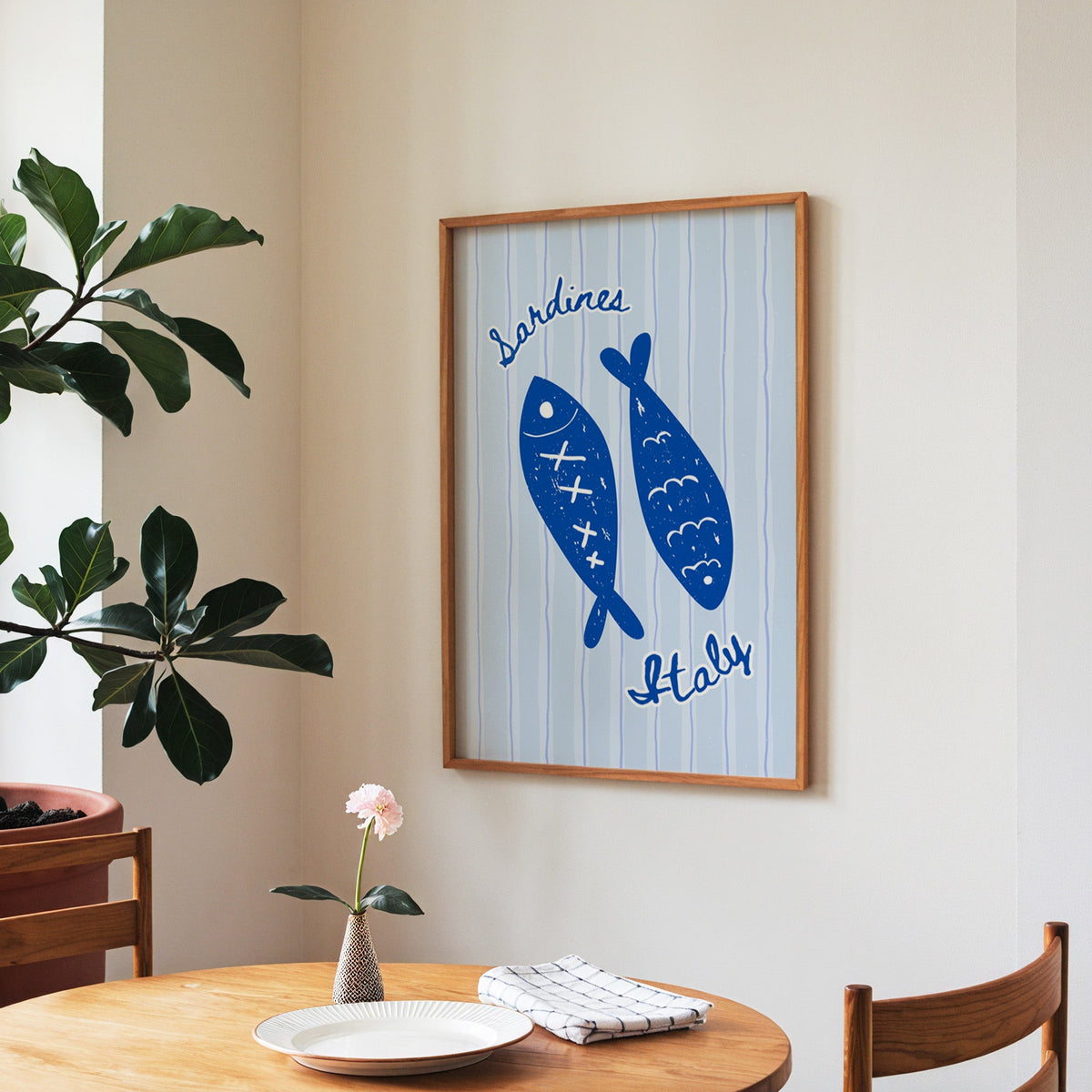 Sardines Italy print in a walnut frame above a round table beside a fiddle-leaf fig