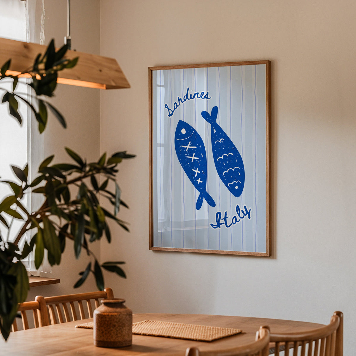Sardines Italy print in a walnut frame above a dining table with olive branches