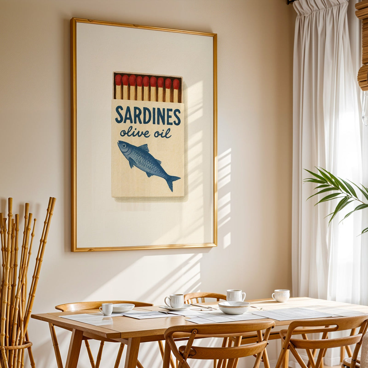 Sardines olive oil matchbox print in a gold frame above a sunlit breakfast table