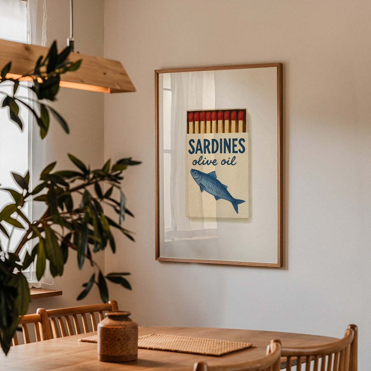 Sardines olive oil matchbox print in a walnut frame above a table beside an olive tree
