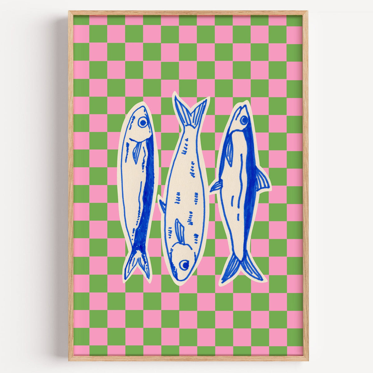 Sardines pink green checker print in a light oak frame on a plain white wall