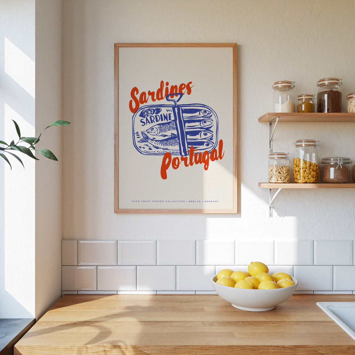 Blue sardine tin print in an oak frame beside open kitchen shelves