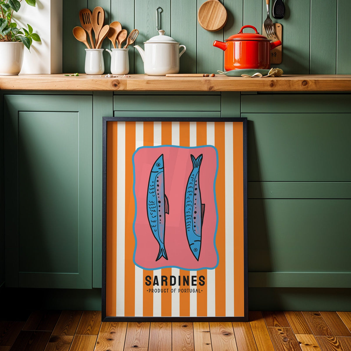 Sardines of Portugal print in a black frame against sage green kitchen cabinets