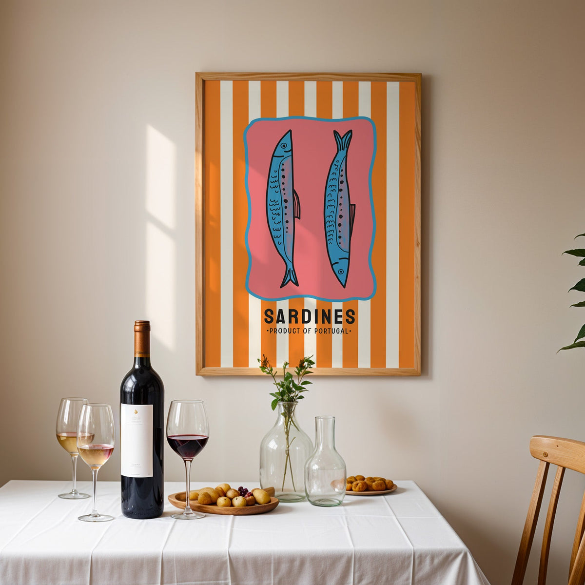 Sardines of Portugal print in an oak frame above a table laid with red wine and glasses