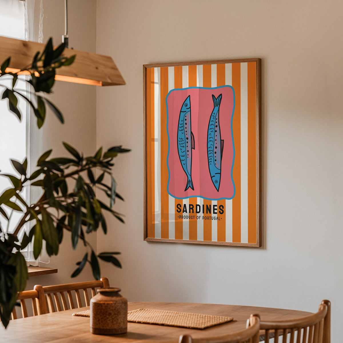 Sardines of Portugal print in a walnut frame above a dining table beside an olive tree