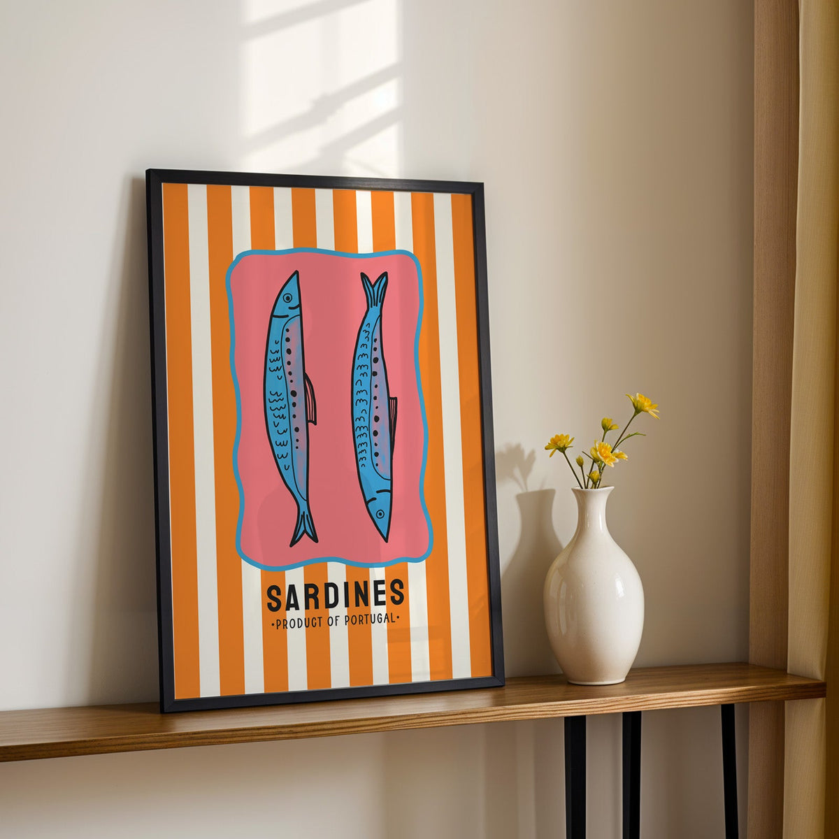Sardines of Portugal print in a black frame on a console table with yellow daisies
