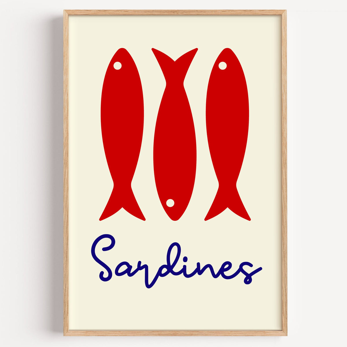 Three red sardines print in a light oak frame on a plain white wall