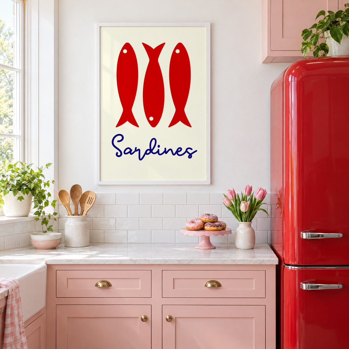 Three red sardines print in a white frame in a pink kitchen beside a red retro fridge