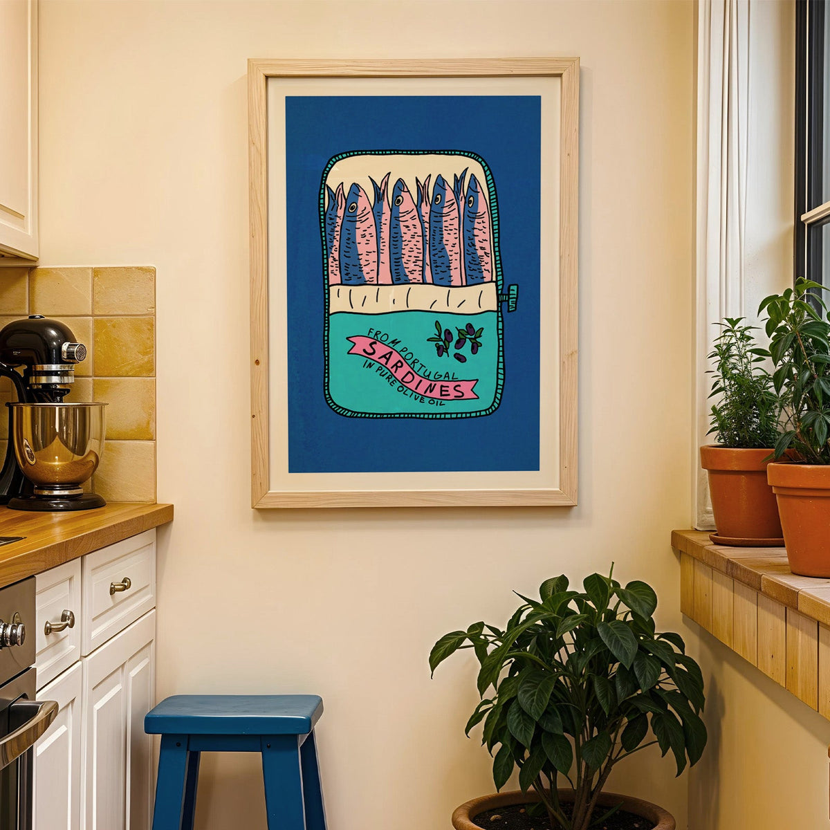 Blue sardine tin print in a wood frame on a yellow tiled kitchen wall